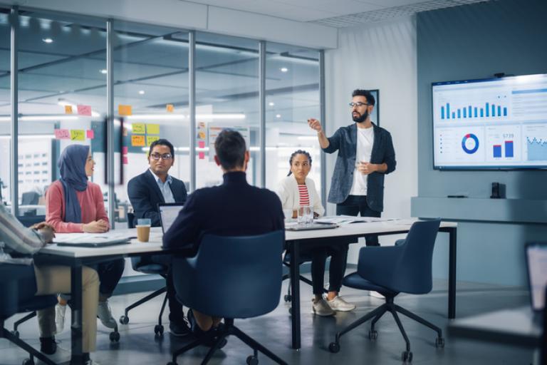A person presenting a meeting using a wall mounted monitor