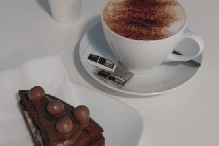A hot drink and cake on a table in the cafe.